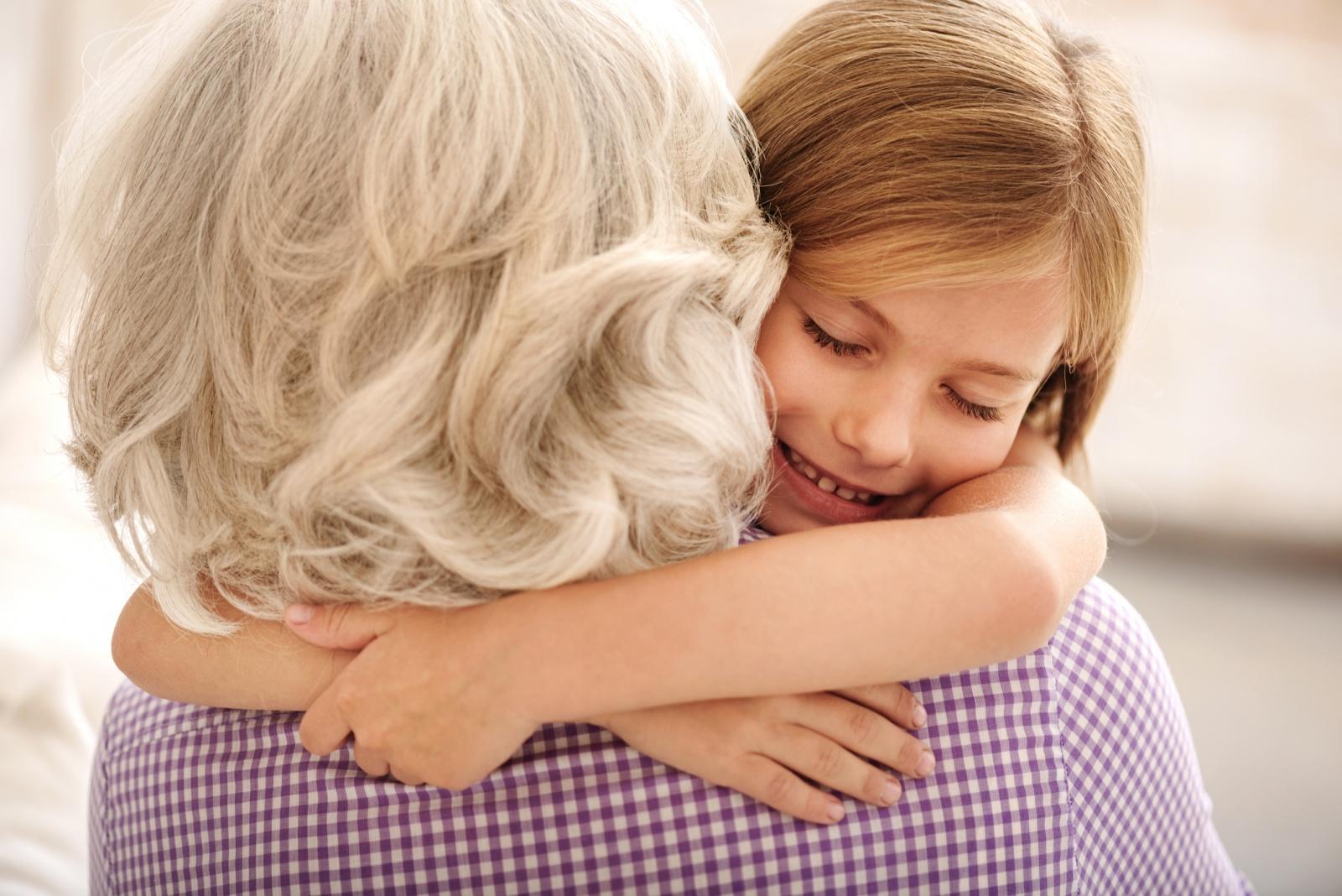 Young girl smiles and hugs an older woman