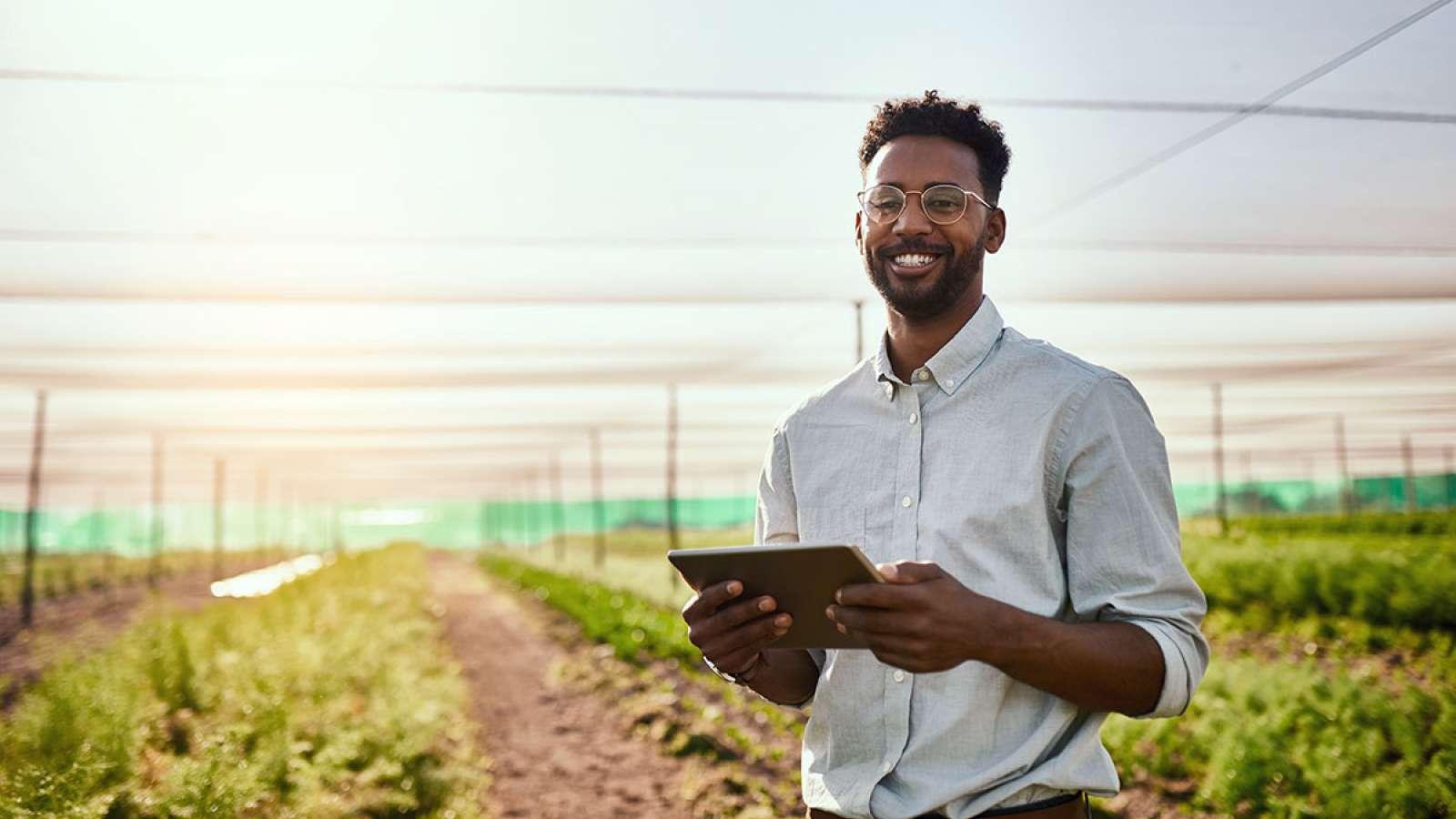 Person holding a tablet standing in an agricultural field