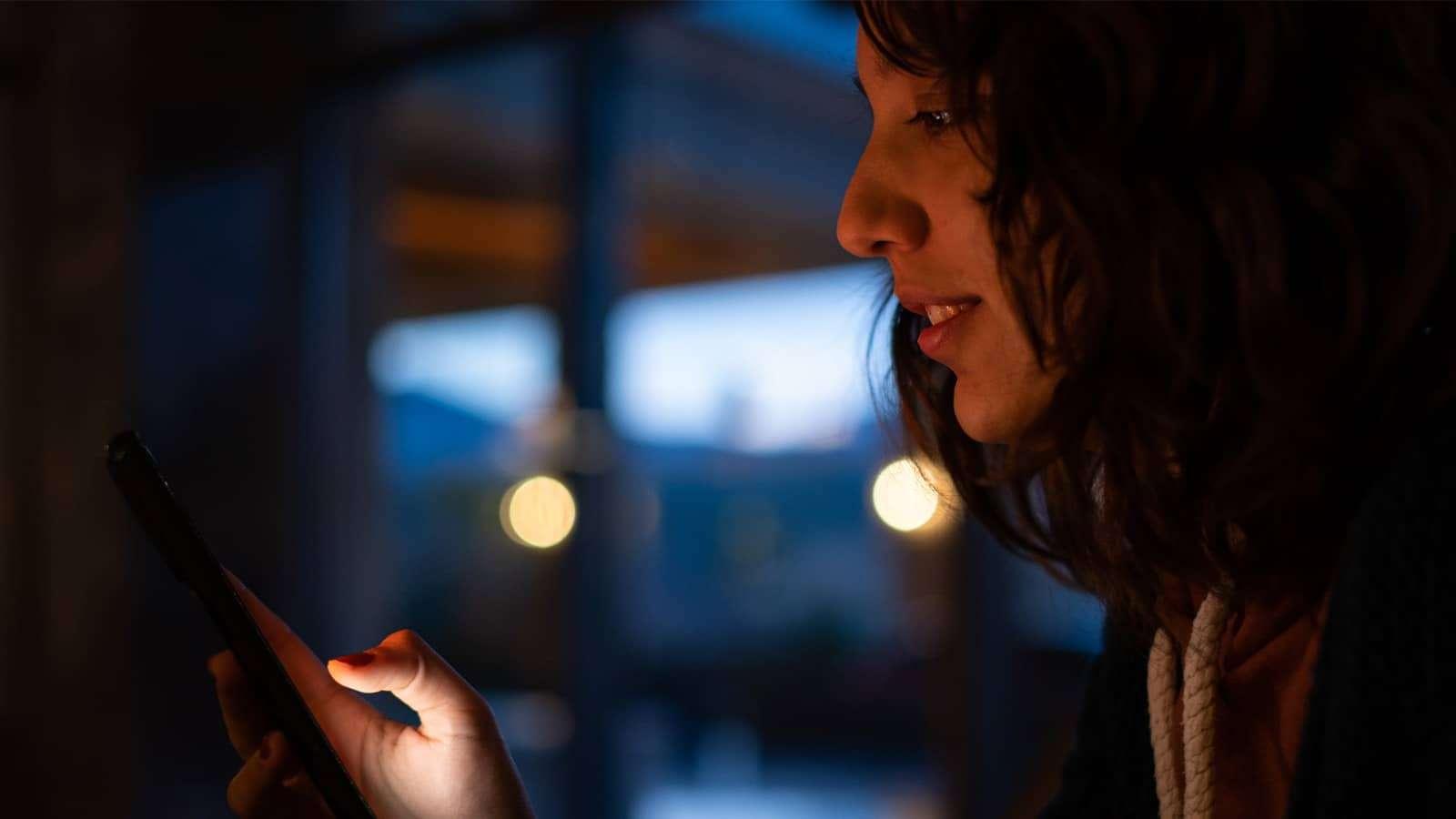 A woman looking at a cellphone she is holding in her hand
