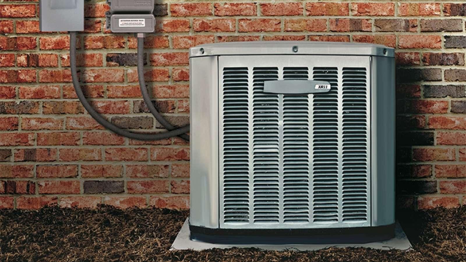 Outdoor air conditioning unit against a brick wall with electrical connections.